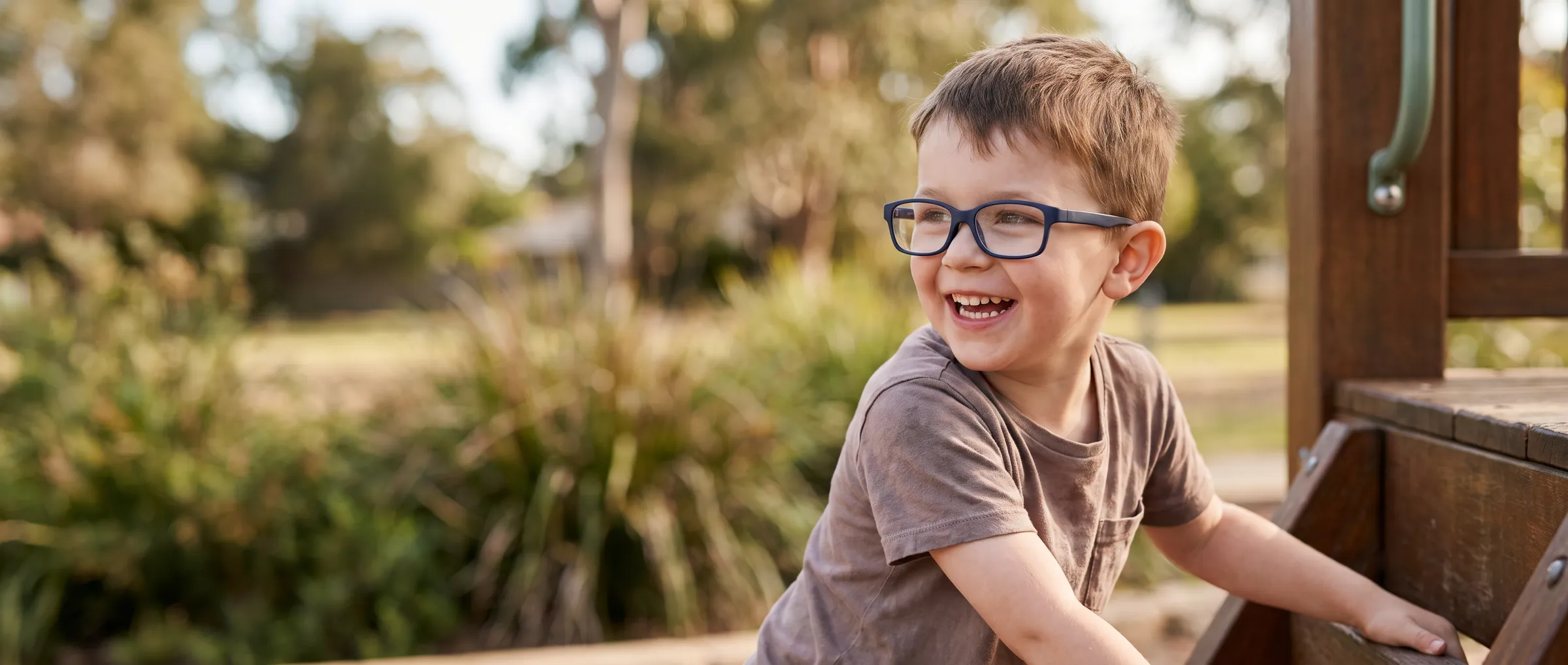 A boy in sturdy children's glasses playing in a park